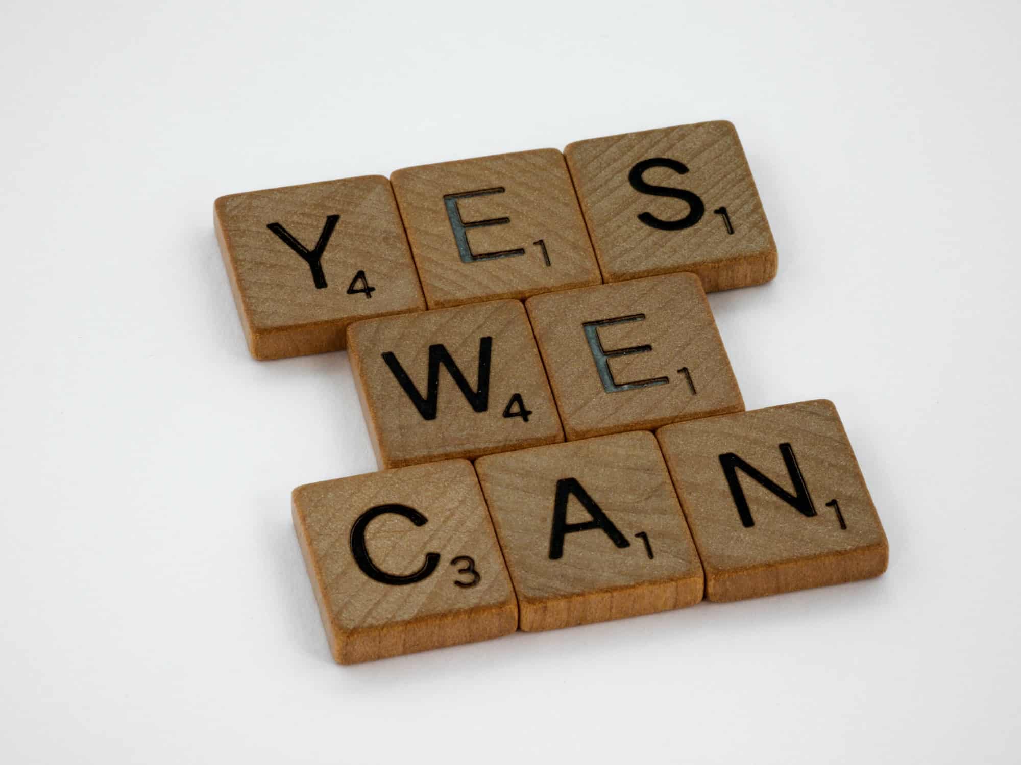 Wooden scrabble tiles that spell out "Yes we can".